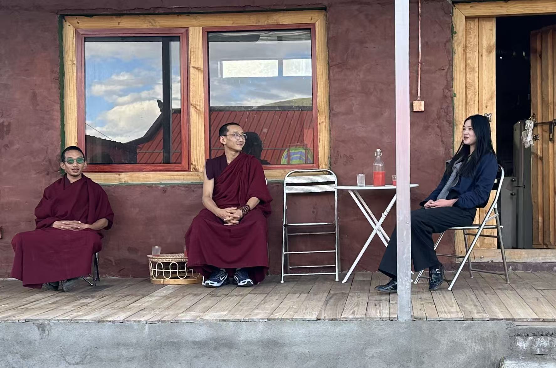 阿逴与两位僧人朋友在屋外木台上对坐